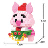 A pink pig figurine made of micro building blocks with a red hat and green accents.