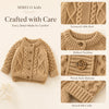 A beige knitted cardigan sweater for kids featuring a textured cable knit pattern, ribbed neckline, wood-style buttons, and s