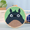 Bordado de fieltro verde con diseño de pájaro negro, montado en un aro de madera.
