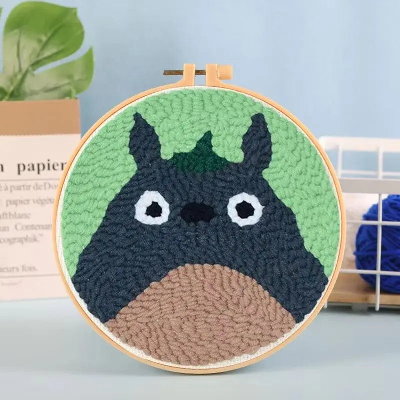Bordado de fieltro verde con diseño de pájaro negro, montado en un aro de madera.