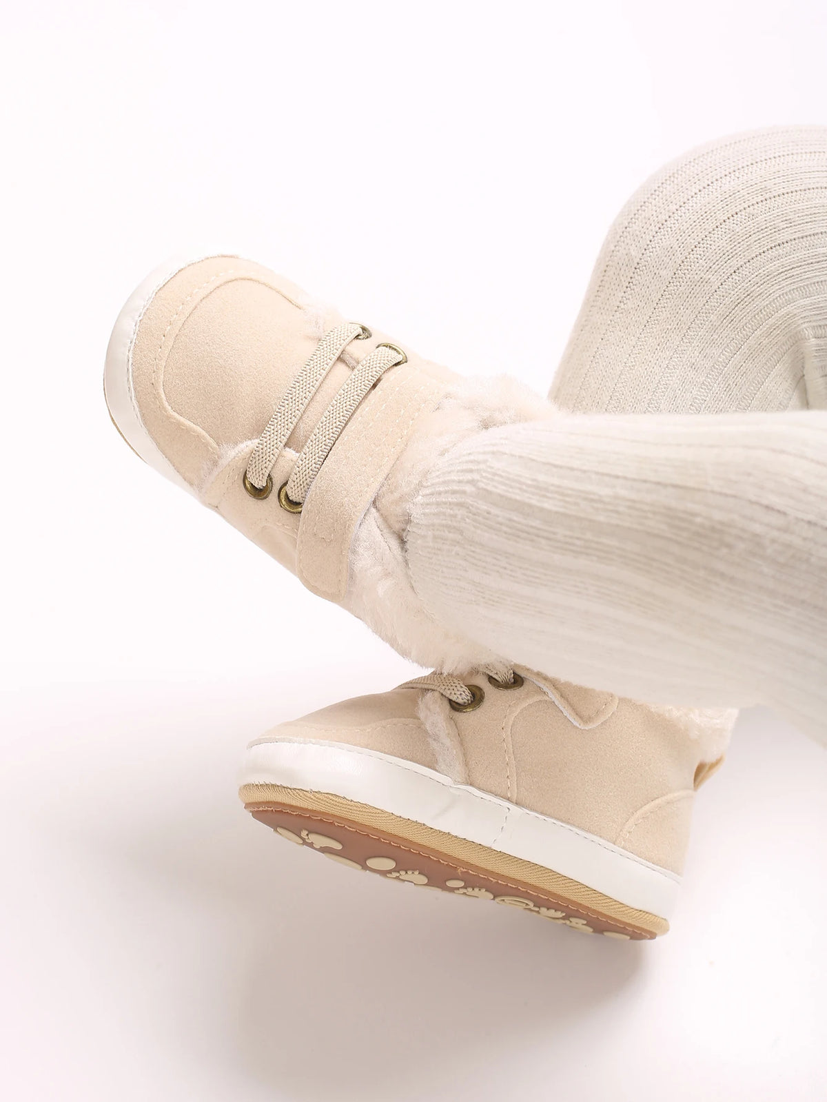 A close-up of beige soft cotton baby winter snow boots worn on a foot.