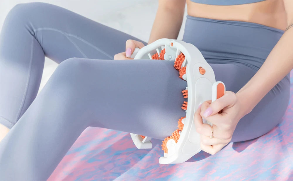 Una persona usa un rodillo de masaje muscular blanco en la pierna, vestida con ropa deportiva azul claro.