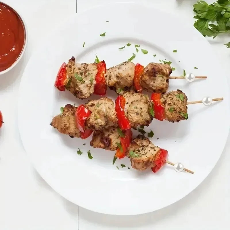 Grilled meat skewers garnished with herbs served on a white plate.