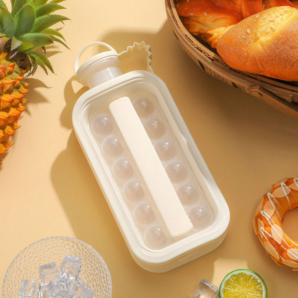 Hvit sammenleggbar isballform for whisky ved siden av en ananas og en brødkurv.