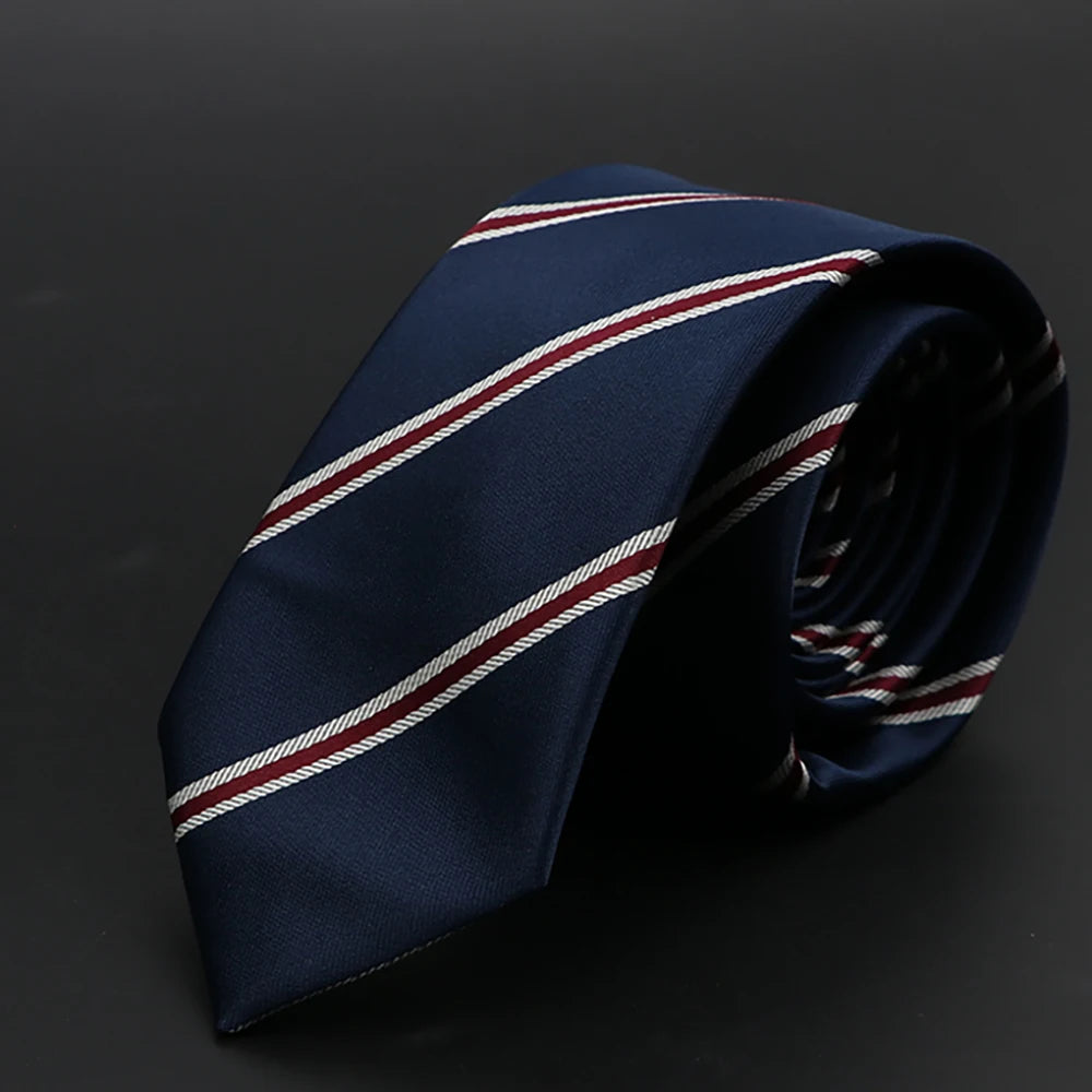 Corbata azul oscuro con rayas diagonales rojas y blancas, plegada sobre fondo oscuro.