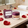 A jar of Calcium Dark Spot Eye Cream next to a red rose petal on a bathroom counter.