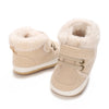 A pair of beige baby winter snow boots with fluffy shearling lining and light tan suede upper.