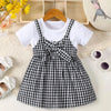 A black and white plaid cotton knit dress for girls with a bow detail, displayed on a light surface.