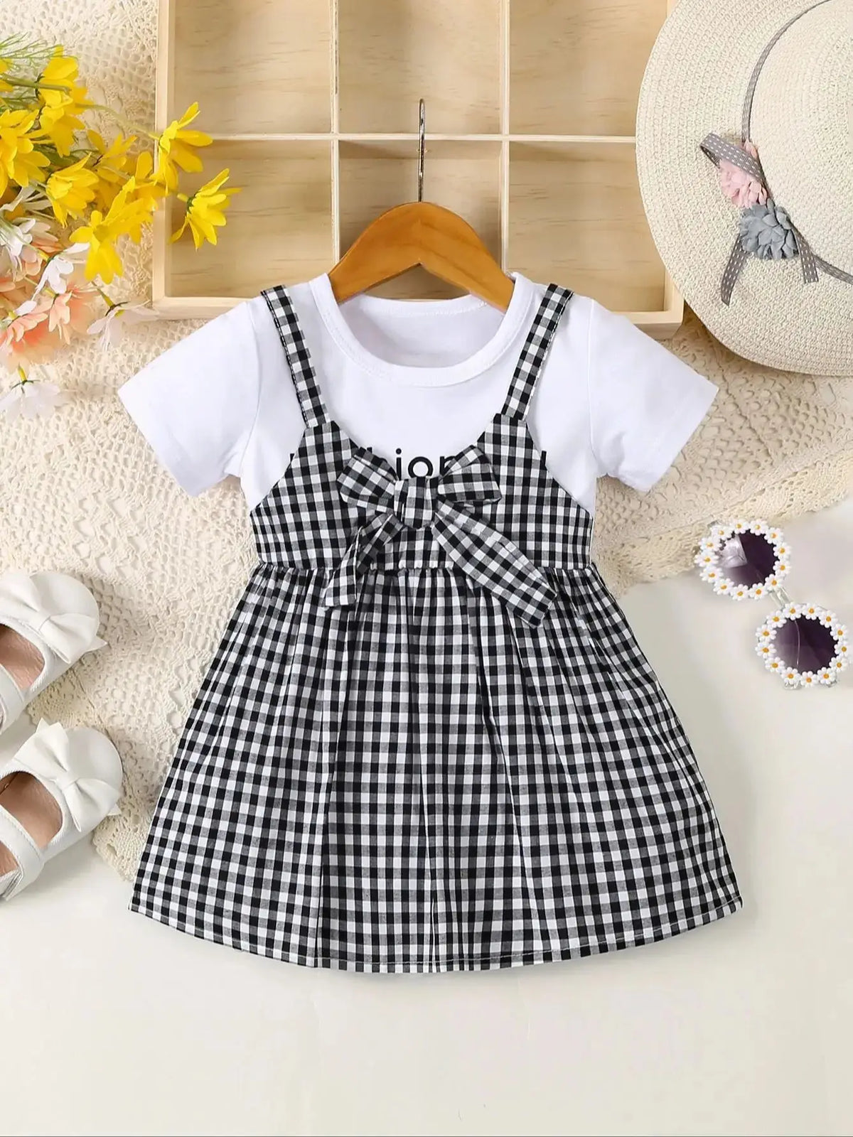 A black and white plaid cotton knit dress for girls with a bow detail, displayed on a light surface.