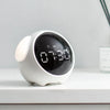 A white, spherical alarm clock with a black display showing 07:30 sits on a white surface.