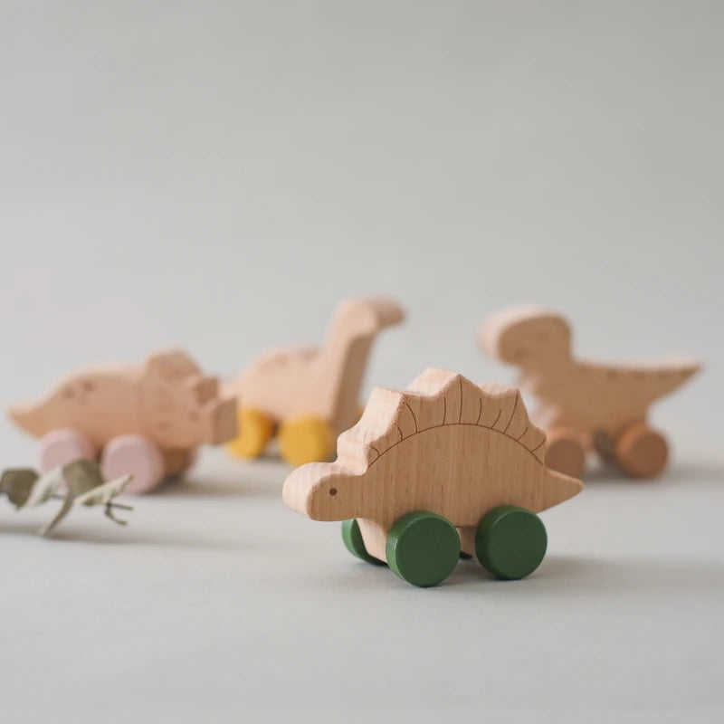A wooden Montessori stacking train toy shaped like an animal, featuring natural wood and green wheels.