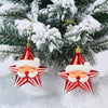A set of two red and white candy cane Christmas tree ornaments hanging on a green pine branch surrounded by white fluffy mate