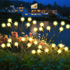 A cluster of glowing yellow solar firefly garden lights with gold accents emerging from green foliage.