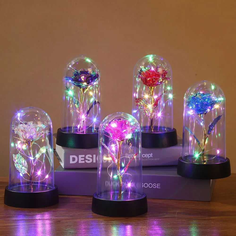 Syv glasskuler med roser og LED-lys på trebunn.