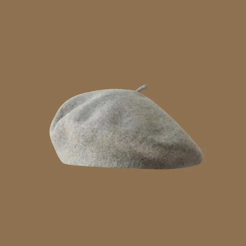 A light gray wool beret hat resting on a plain brown background.