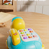 A yellow and blue musical turtle crawling toy with a phone feature resting on a wooden table.