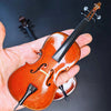 Une main tient un violoncelle miniature en bois avec un archet et un support sur fond sombre.