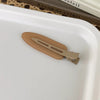 A pair of matte resin side hair clips resting on a white tray.