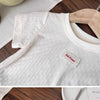 A white girls cotton lace hem short sleeve t-shirt displayed on a wooden hanger.
