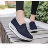 Mujer con zapatos azul marino de suela blanca y pantalón negro, de pie al aire libre.