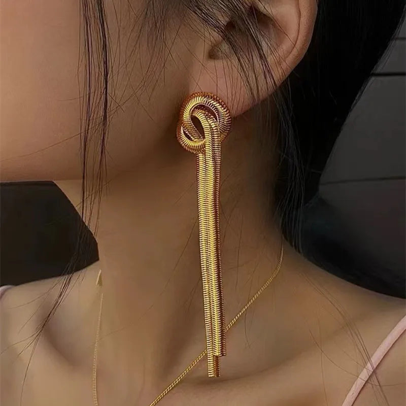 Gold geometric tassel drop earrings hanging from a delicate gold chain