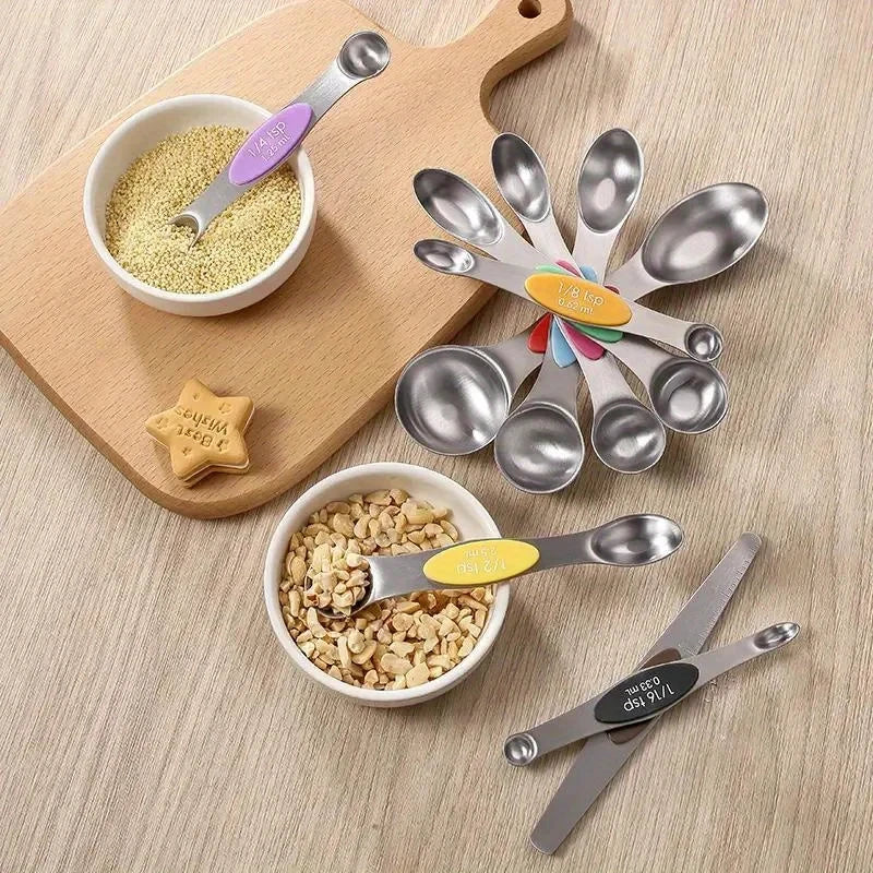 A stainless steel double-headed measuring spoon set with magnetic storage is displayed on a wooden cutting board.