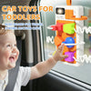 A toddler is interacting with a colorful Montessori busy board for travel featuring auction cups and lights.