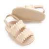 A pair of light beige baby girls' summer sandals with bow embellishments and soft faux fur trim.