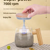 A hand is stirring a dark liquid in a glass mug using a blue self-stirring mechanism with a wooden handle.