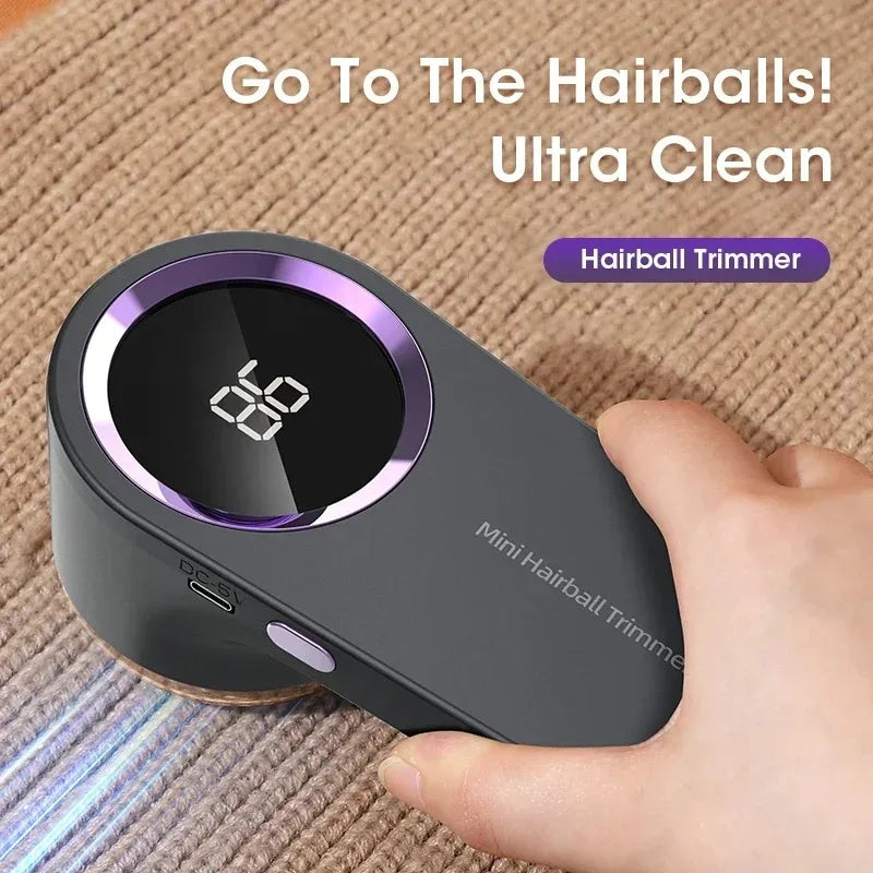A hand holds a Mini Hairball Trimmer device with a dark gray body and purple accents, demonstrating its use.
