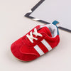 A pair of red and white baby first walker shoes with a TPR sole resting on a white surface.