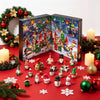 Rød adventskalenderboks med resin-julefigurer og grønt på en festlig baggrund.