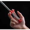 A hand is holding a flexible drain snake with a red handle and silver wire, against a black background.