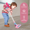 A young child is playing with a pink interactive toy vacuum cleaner on a floor, demonstrating coordination and imagination sk