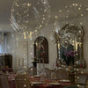 A ceiling display of clear balloons filled with twinkling LED lights in an elegant room setting.