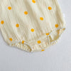 A light yellow baby cotton jumpsuit with scattered orange polka dots