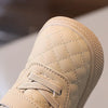 Close-up of a beige baby winter snow boot with a quilted texture and Velcro closure.