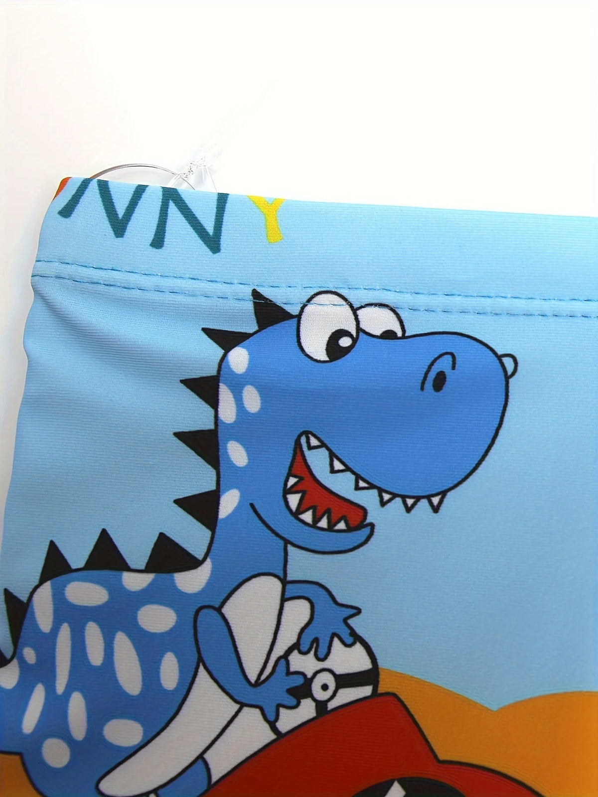 A blue dinosaur graphic on a swim trunk fabric.