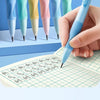 A hand holds a light blue mechanical pencil pen writing on lined paper, with several colored lead refills visible in the back