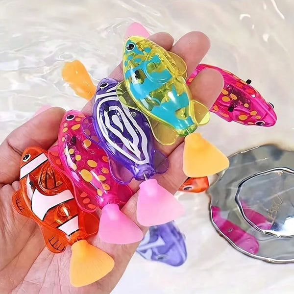 A hand holds a collection of colorful photosensitive robotic clownfish toys in various shades of yellow, pink, purple, and gr