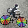 A black and white cat wind spinner decoration mounted on a bicycle wheel.