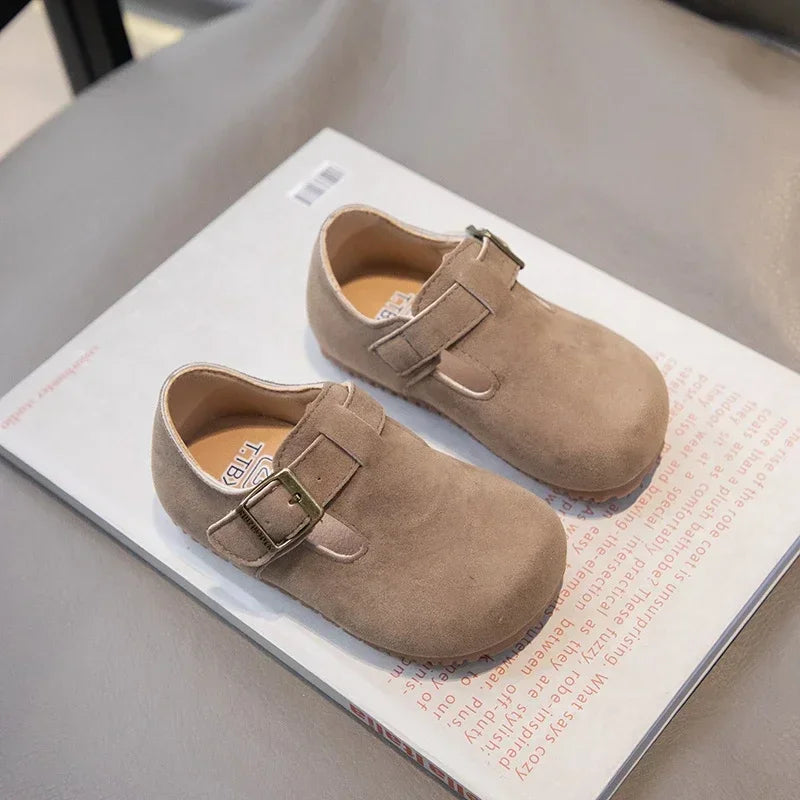 A pair of tan retro non-slip kids' moccasin shoes with an easy hook-and-loop closure displayed on a white card.