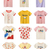 A collection of ten girls' printed short-sleeve cotton t-shirts featuring various seasonal and fruit designs.