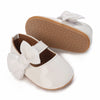 A pair of white baby first walker shoes with a light brown sole and bow detail.