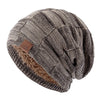A beige and brown knit slouchy beanie with a multicolor pattern and a faux fur trim.