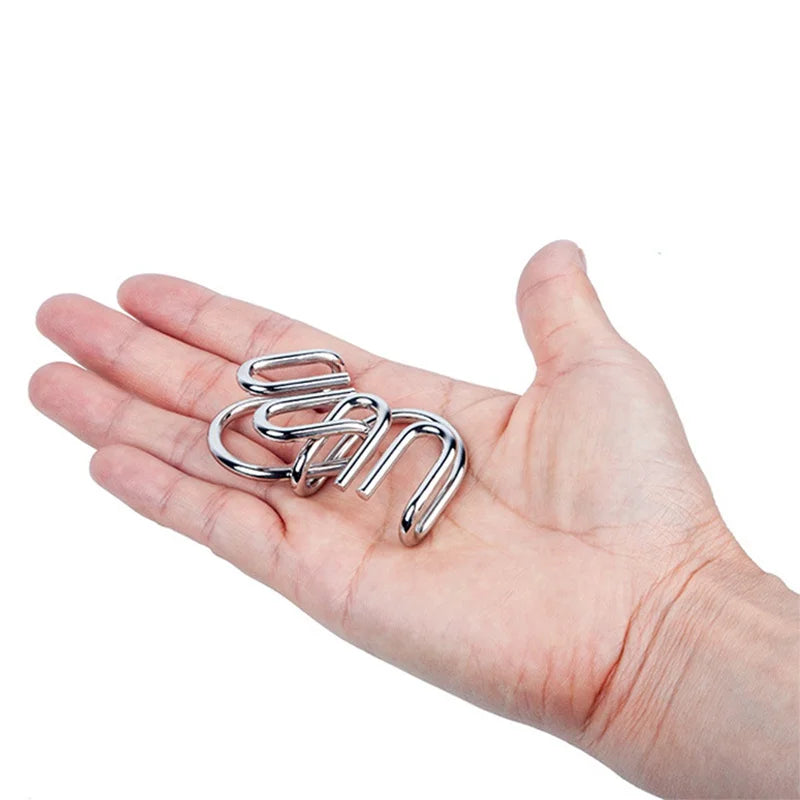 A hand holds a set of eight silver metal wire puzzle brain teasers.