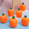 Juguete de zanahoria naranja exprimible con tallo verde sobre superficie blanca.