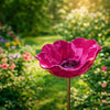 A handcrafted metal flower garden stake shaped like a deep pink, ruffled bowl or bird bath in a lush green garden setting.