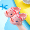 Pink kids shark clog sandals with anti-slip sole being held by a hand