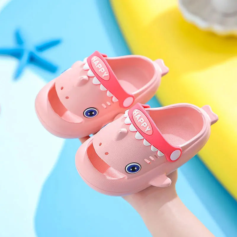 Pink kids shark clog sandals with anti-slip sole being held by a hand